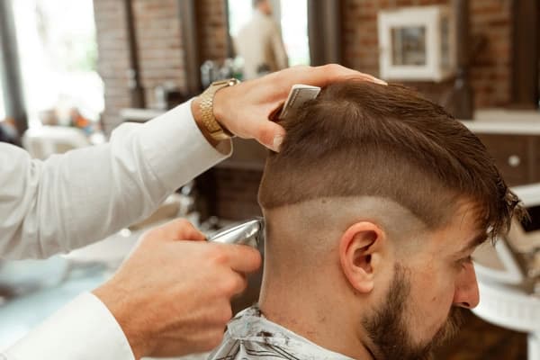 Stockfoto eines Friseurs beim Haareschneiden in einem Barbershop